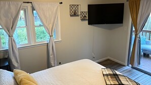 A bedroom with a bed, curtains, a TV mounted on the wall, and a window with a view. - The Resorts World Retreat Spacious 4-bedroom house in beautiful Monticello (Monticello)
