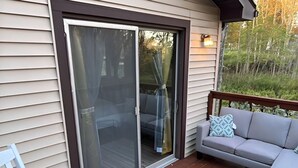 A deck with a sliding glass door, a white rocking chair, and a gray sofa. - The Resorts World Retreat Spacious 4-bedroom house in beautiful Monticello (Monticello)