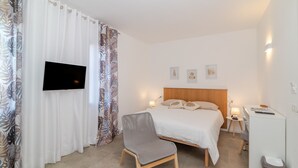 Une chambre d’hôtel équipée d’un lit, d’une télévision, d’une chaise, d’un bureau et d’une poubelle.
