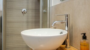 Une salle de bain avec un lavabo blanc, un robinet chromé et un flacon de lotion.