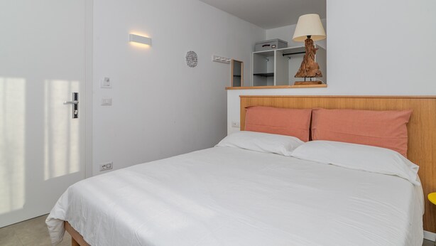 Ein Schlafzimmer mit einem Bett, einer Nachttischlampe, einem Kleiderschrank und einem Spiegel.