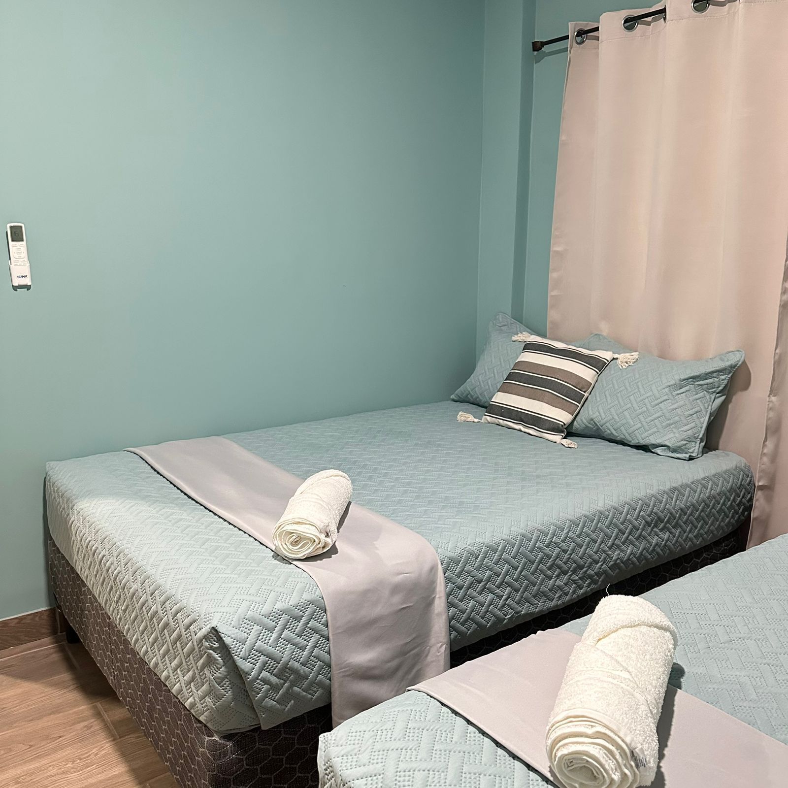 A room with two beds, each with a quilted bedspread and a rolled white towel.