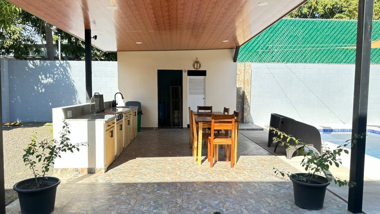 Un patio al aire libre con mostrador de cocina, mesa y sillas para comer.