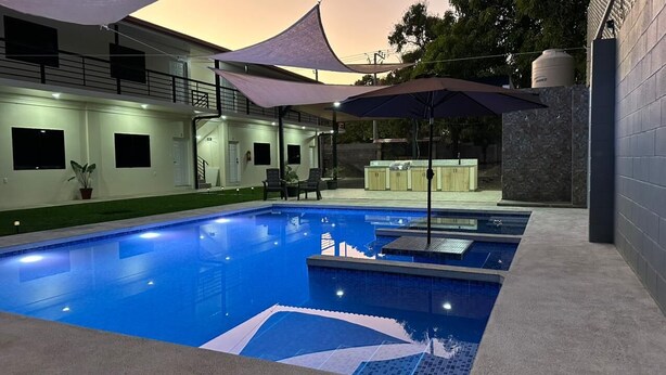 A swimming pool with multiple lanes, a covered seating area, and a bar. - CHURROS (La Libertad)