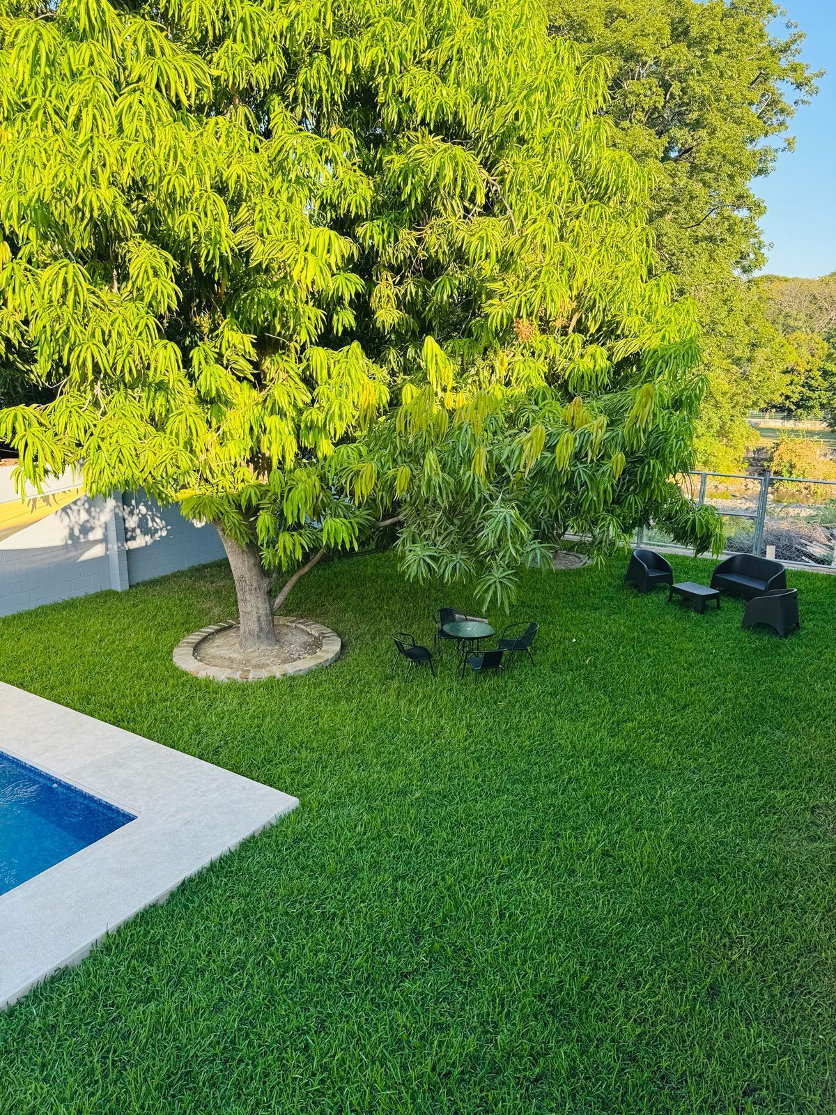 Zona exterior ben cuidada amb piscina, gespa i zona d'estar amb cadires i taules.