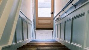 Una escalera con acabado de madera que lleva a una puerta con un panel de vidrio esmerilado.