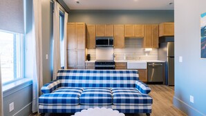 Una cocina compacta con armarios de madera, microondas, estufa, pileta y electrodomésticos de acero inoxidable.