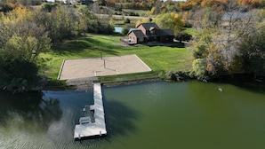A riverside property with a dock, a grassy area, and a house in the background.