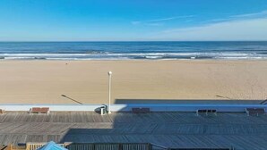Une vue sur la plage depuis un balcon doté d’une terrasse en bois, d’un lampadaire et d’une rambarde.