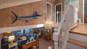 Un interior de madera con comedor, candelabro y escalera.