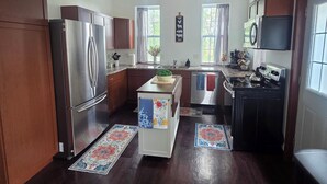 Une cuisine dotée de meubles en bois, d’un réfrigérateur en acier inoxydable, d’une cuisinière et d’un ventilateur de plafond.