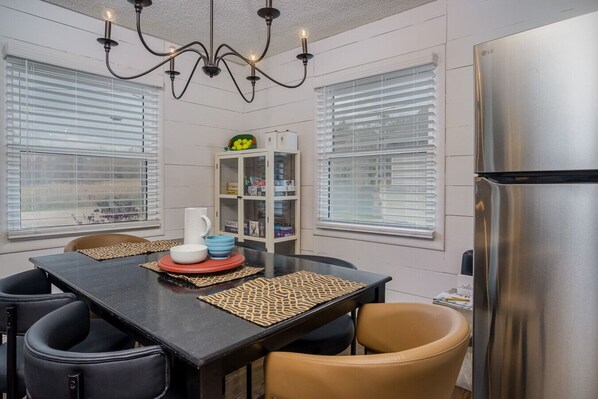 A modern kitchen with a dining table, chairs, a chandelier, and a refrigerator. - Center Lake Cape Cod Escape Waterfront Home with Dock, Scenic Views, and Pet Friendly (Salem Lakes)