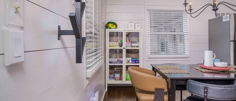 A compact kitchen with a dining area, white walls, a built-in cabinet, and a window with blinds.