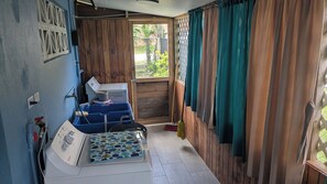A compact kitchen with a washing machine, a sink, and a window with curtains.