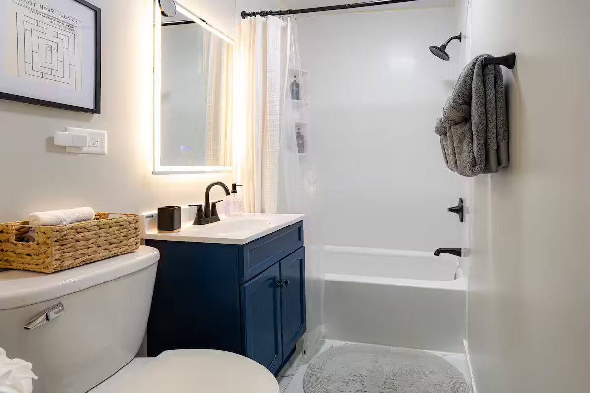 A bathroom with a toilet, sink, mirror, and bathtub.