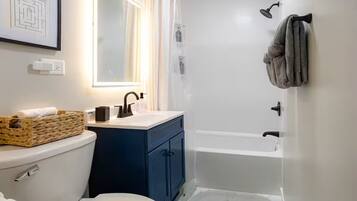 A bathroom with a toilet, sink, mirror, and bathtub.