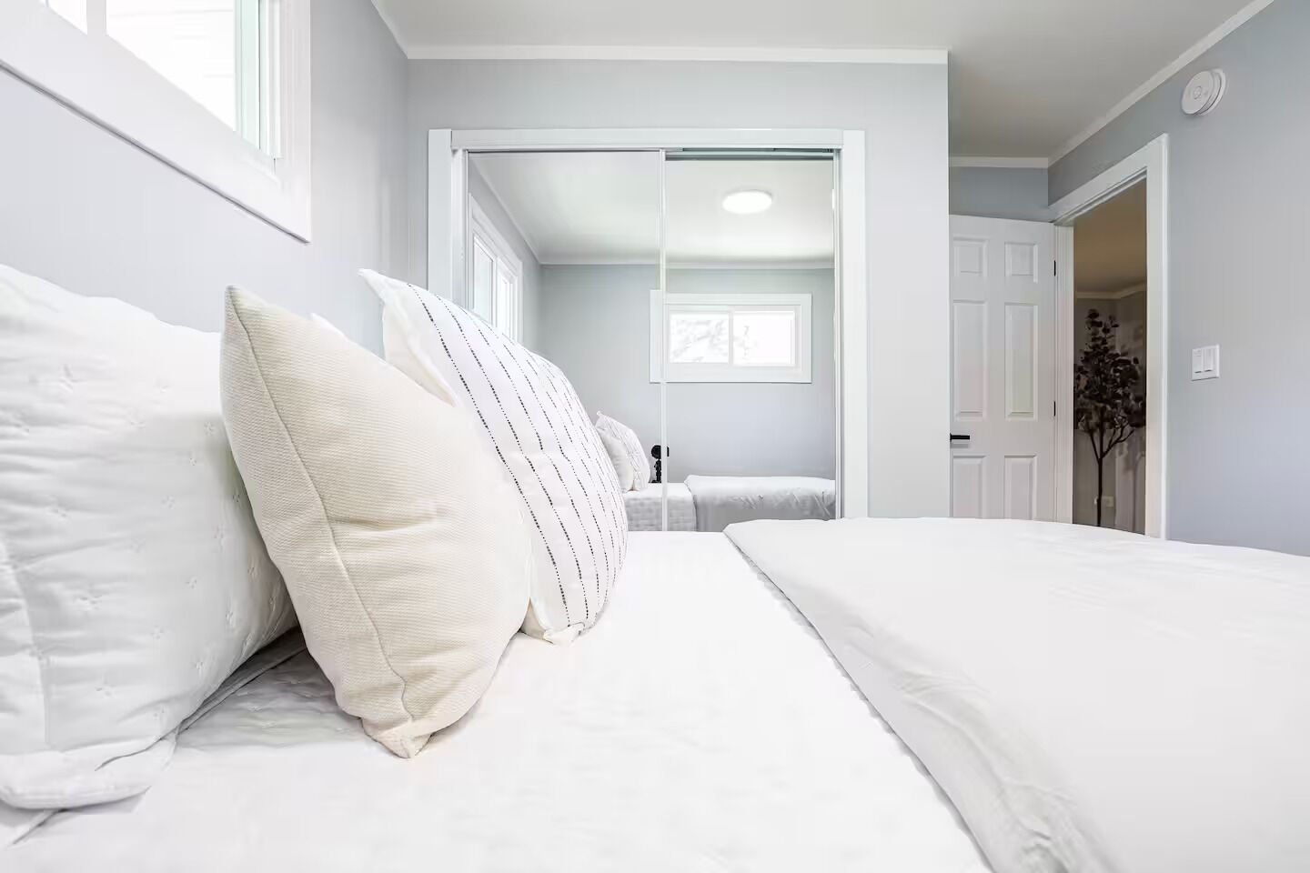 Un dormitori amb llit, almoinos, un armari i una porta que dona a una altra habitació.