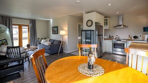 A modern kitchen with a built-in oven, microwave, and stainless steel range hood. There is a dining table with a wine glass and a placemat. - bbbbbnnbbb (Medford)