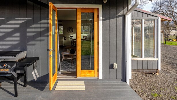 A house with a wooden door, a small patio with a table and chairs, and a window. - bbbbbnnbbb (Medford)
