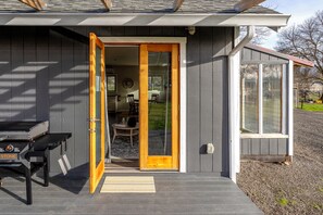 A house with a wooden door, a small patio with a table and chairs, and a window.