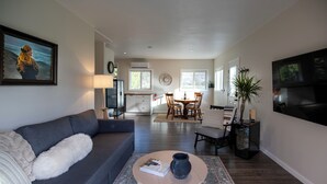 A modern living room with a grey sofa, a round coffee table, and a dining area with wooden chairs and a table. - bbbbbnnbbb (Medford)