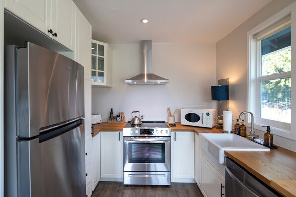 A modern kitchen with stainless steel appliances, white cabinetry, and a window providing natural light.