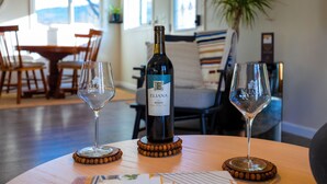 A table with a bottle of Eliana Merlot wine and two glasses on coasters. - bbbbbnnbbb (Medford)