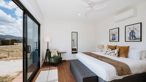 Quarto de hotel moderno com uma cama grande, uma mesa de trabalho e vista para o exterior.