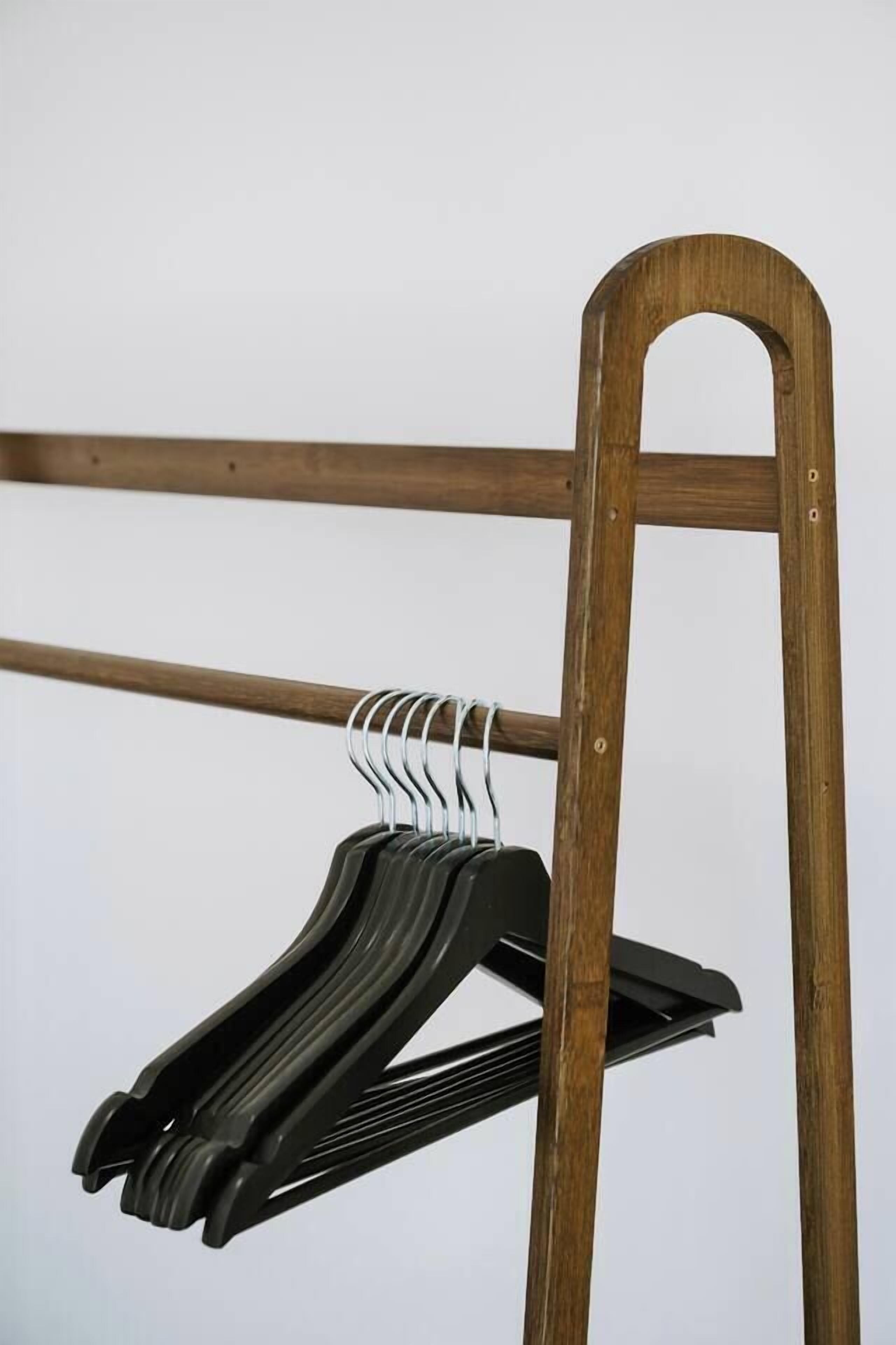 A wooden coat rack with multiple black hangers.