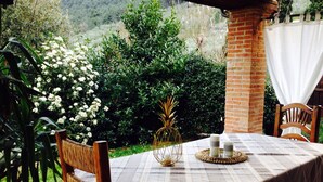 A patio with a table set for two, surrounded by greenery and a brick wall.