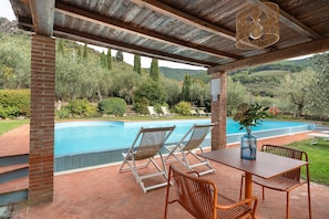 A covered outdoor area with a pool, lounge chairs, and a table with a vase. - Studio Apartment 'Il Nido Di Delia' with Shared Pool, Private Terrace and Wi-Fi (Buti)