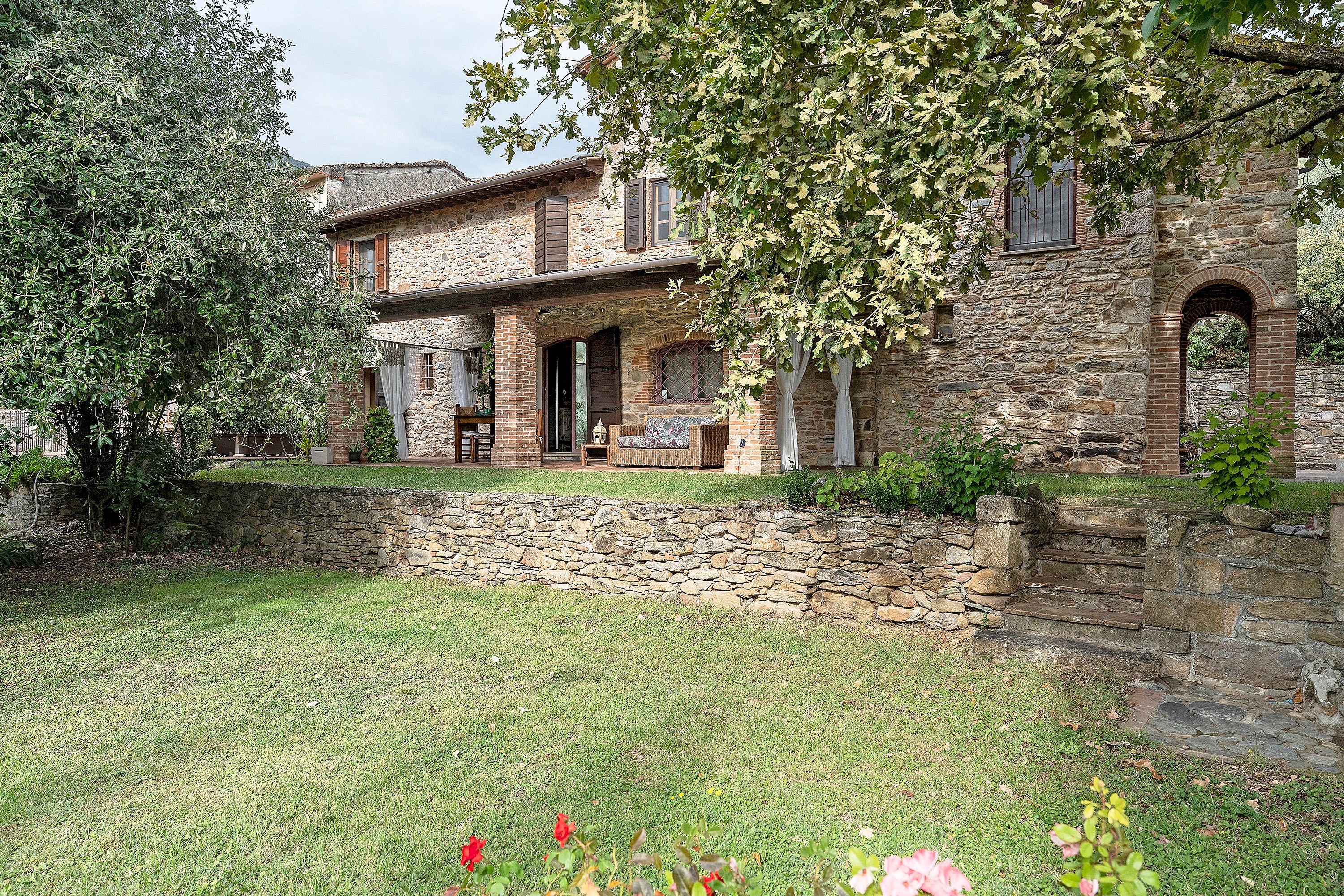 A stone building with a covered porch and a stone wall.