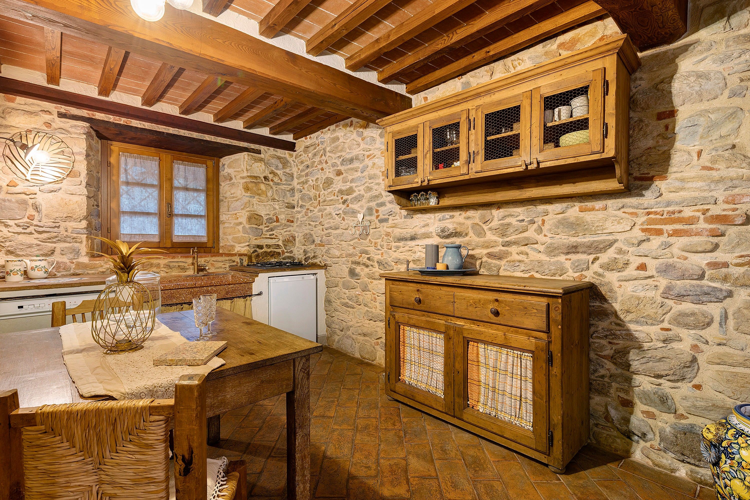 Eine rustikale Küche mit Steinwänden, Holzschränken und einem Holztisch.