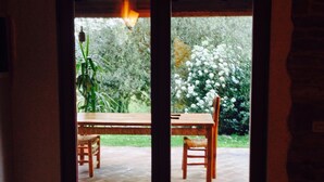 A room with a wooden table and chairs, a sliding glass door leading to an outdoor patio with a brick floor.