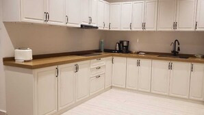 Una cocina con armarios blancos, encimera de madera, tostadora, cafetera y refrigerador.