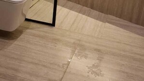Un baño moderno con ducha, inodoro y estante con artículos de aseo.