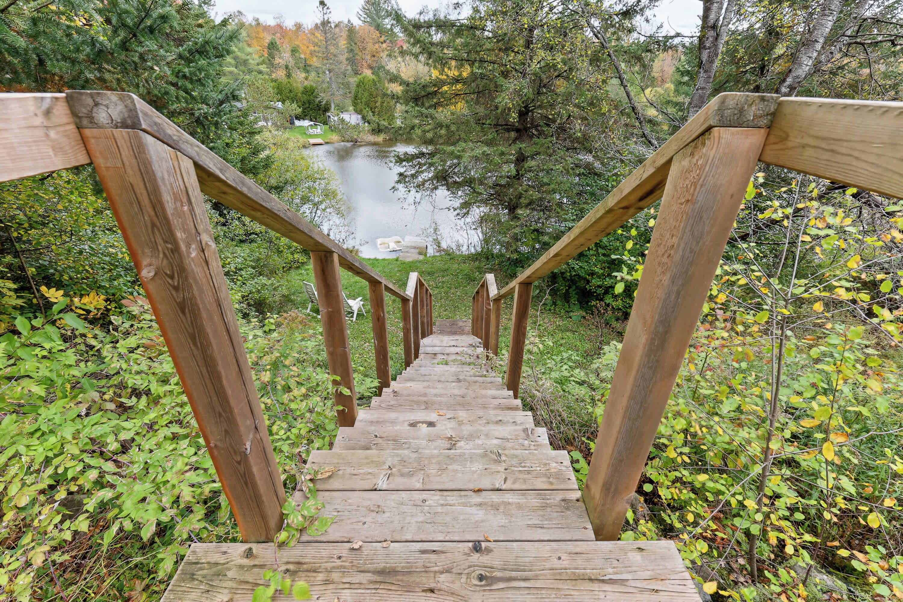A wooden staircase leading to a bridge over a body of water, surrounded by greenery.