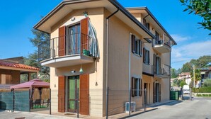 Un edificio de dos pisos con balcones, una entrada con reja y cielo despejado.