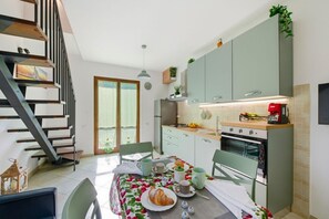 Cocina moderna con una mesa de comedor para dos personas, una escalera y vistas al exterior.