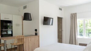 A modern hotel room with a bed, a desk with a chair, a TV, and a window with curtains. - Château de L'Insolas (Villeneuve-lès-Avignon)