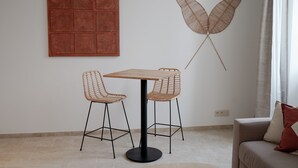A modern living room with a round table and two wicker chairs, a decorative wall piece, and a sofa with a cushion. - Château de L'Insolas (Villeneuve-lès-Avignon)