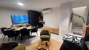 Uma sala de estar moderna com área de jantar, TV de tela plana e uma escada.