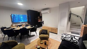 Ein modernes Wohnzimmer mit Essbereich, einem Flachbildfernseher und einer Treppe.