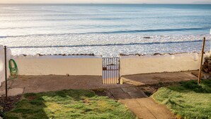 Blick auf die Küste mit einem Tor zum Strand, einem Gartenschlauch und einem Betonweg.