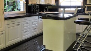 Cocina moderna con armarios blancos, encimera negra y una isla central.