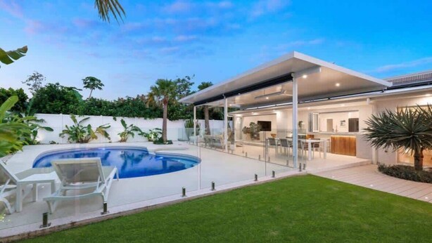 A modern house with a swimming pool, covered patio, and a well-maintained lawn. - Casa Palma in Mermaid Waters (Gold Coast)
