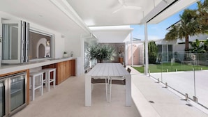 A modern kitchen with a dining area, large windows, and a view of the backyard. - Casa Palma in Mermaid Waters (Gold Coast)