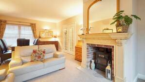 A living room with a fireplace, a sofa, a dining table, and a large mirror. - Host Stay Amberleigh (Seahouses)