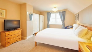 A hotel room with a large bed, a television on a wooden dresser, a wardrobe, and a window with curtains. - Host Stay Amberleigh (Seahouses)