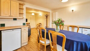 Cocina compacta con armarios de madera, lavavajillas integrado y comedor con mesa preparada para cuatro.